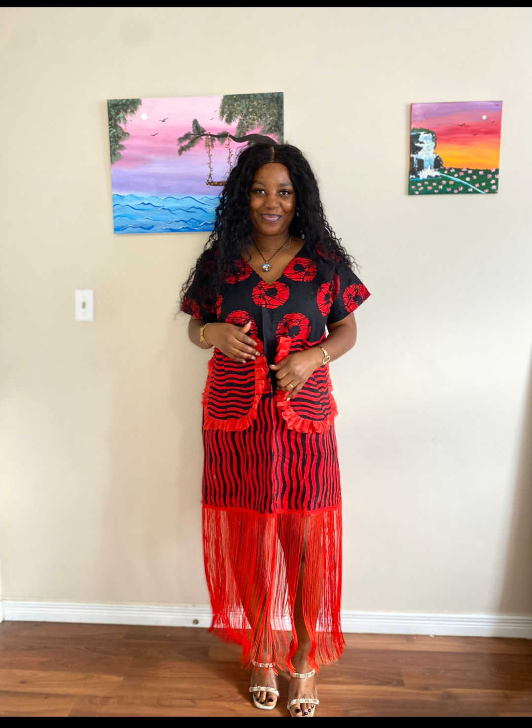 Model wearing the Crimson Bloom Ankara Fringe Dress in red and black with cascading fringe hem